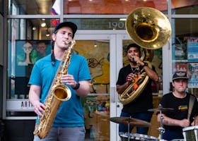 A lively street jazz band with saxophone, tuba, and drums performing outdoors.